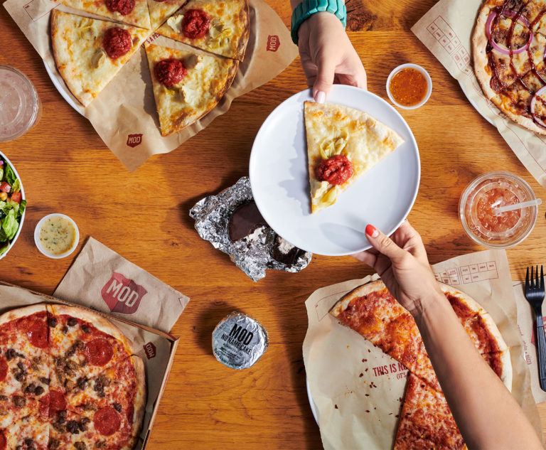 A table with pizza and no name cake.